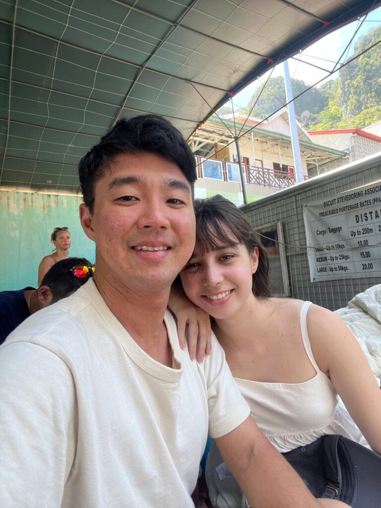 Couple waiting outdoors for the el nido to coron ferry by Atienza