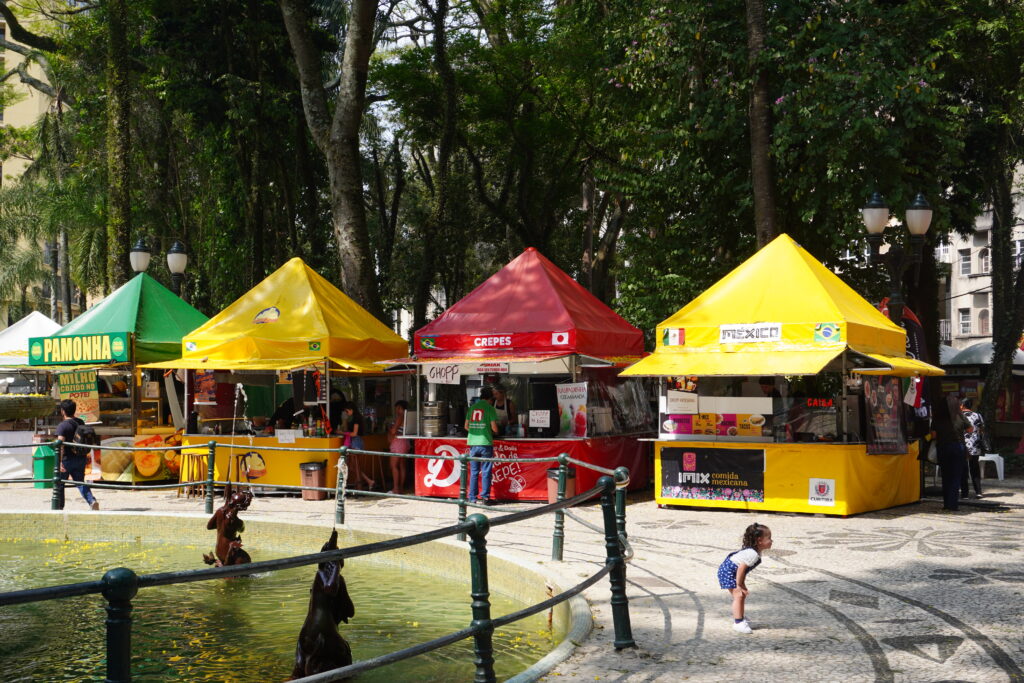 Four street food vendors and a water fountain in the center of Praça Onório