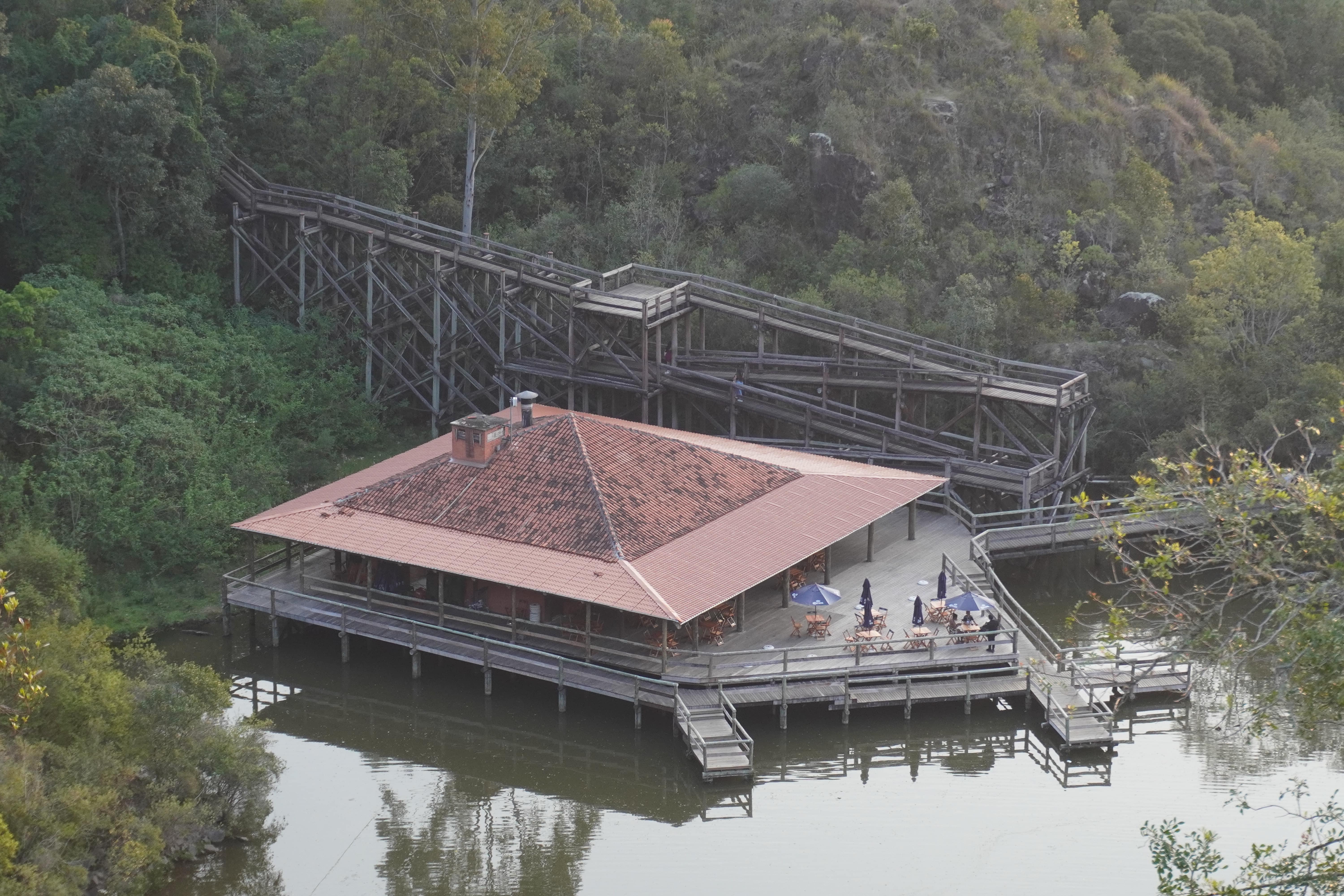 Above-water square-shaped restaurant accessible through a 2-level wooden ramp.