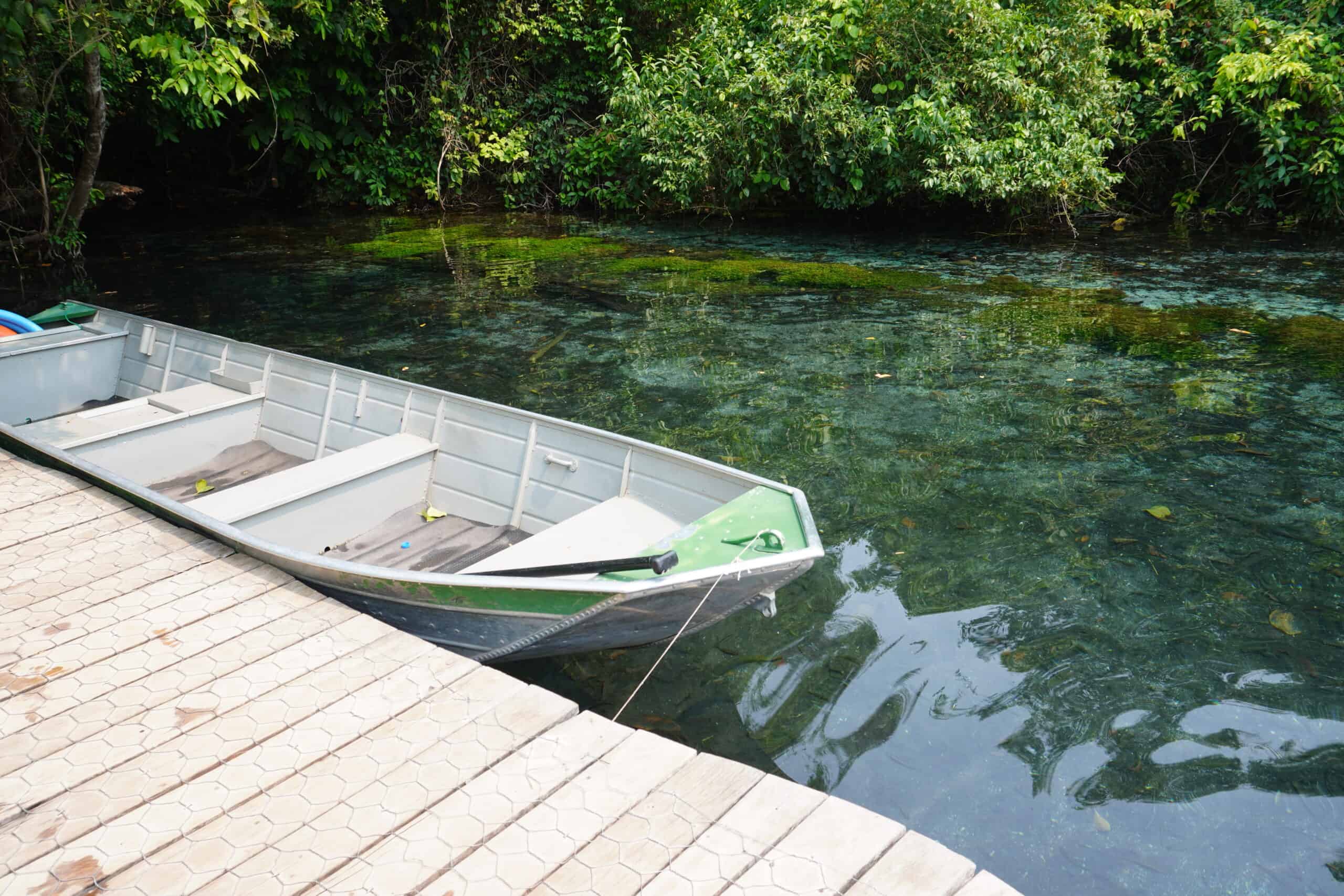 Boat in deck in a river in Bonito. The water is completely see through and have a blue tone