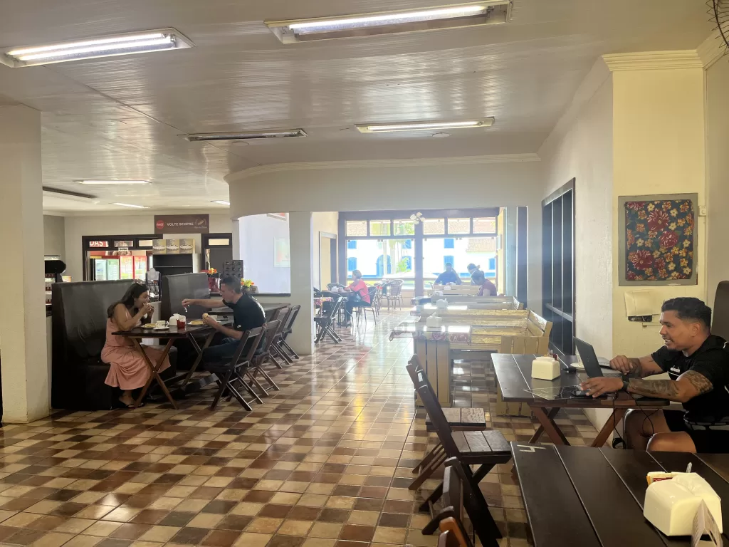 Indoor seating area at Pão da Praça in downtown Chapada dos Guimarães. It is possible to see the town's landmark Church through a big window.