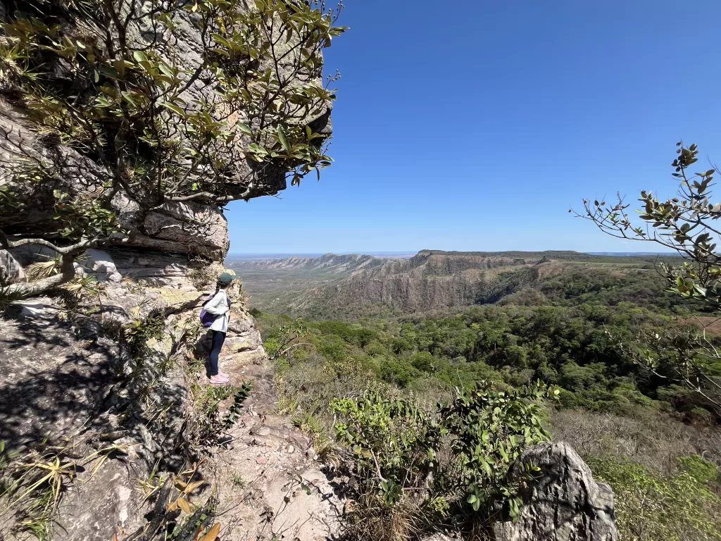 Girl standing at sandstone rock formation and looking into the landscape of Chapada dos Guimaraes