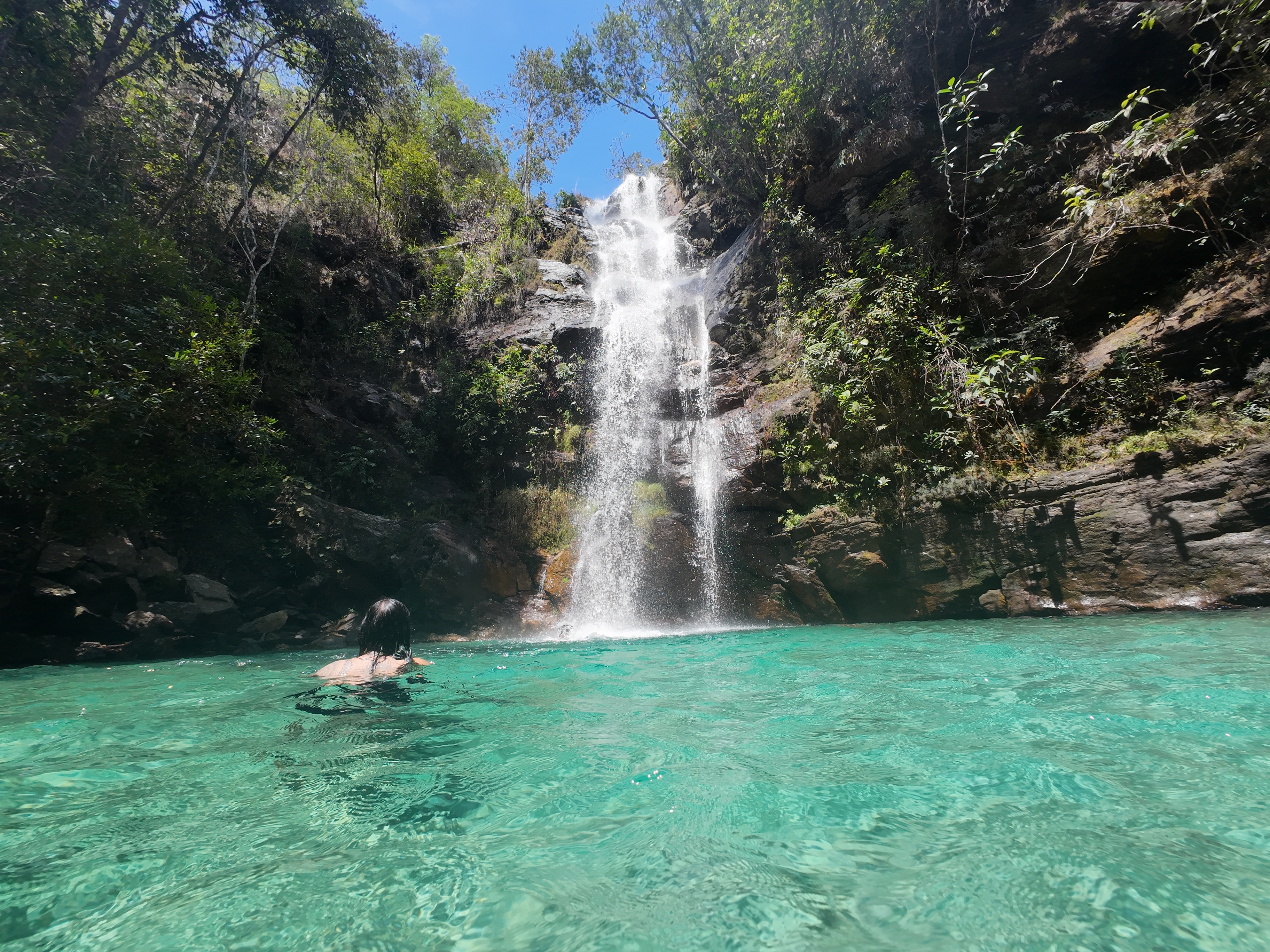 Man swimming inside the bright blue waters of Cachoeira Santa Barbara at Chapada dos Veadeiros