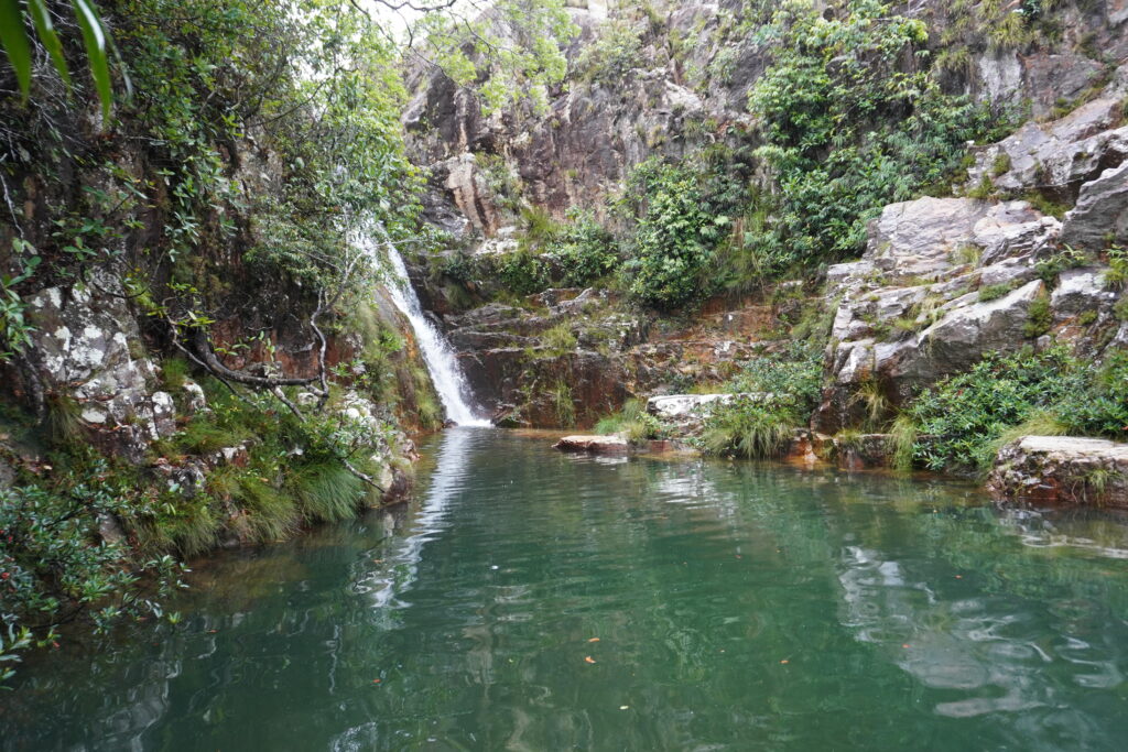 Thin waterfall with a pool of emerald green water at Complexo do Prata