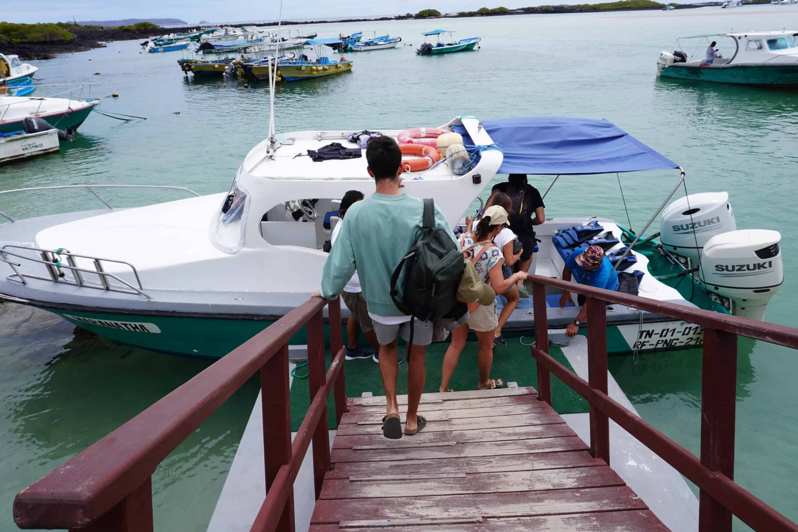 People boarding a motorboat in the pier. 6 people are seen entering the boat.