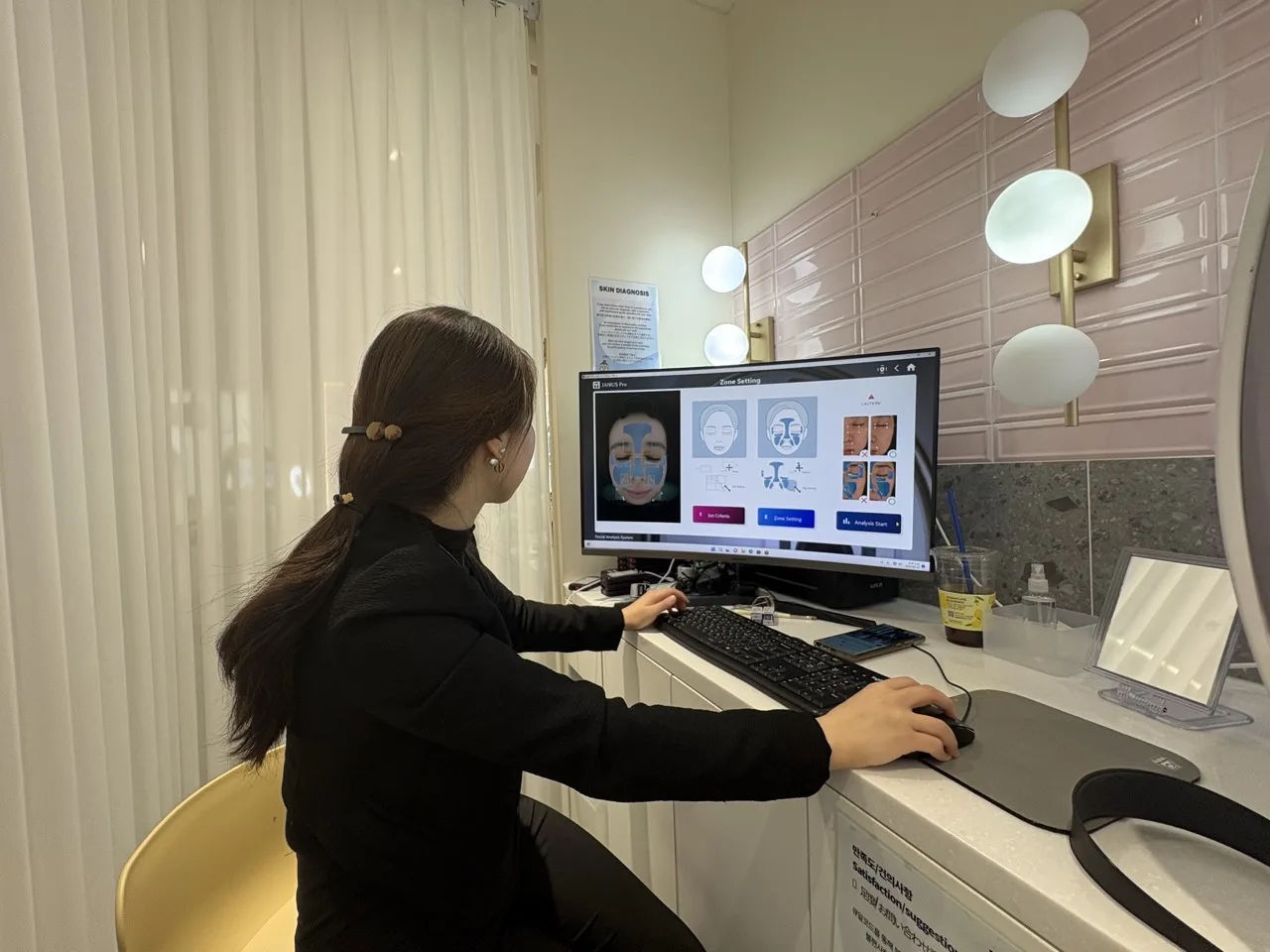 Professional at BeautyPlay Seoul looking into a computer screen to conduct a skin analysis on the patient