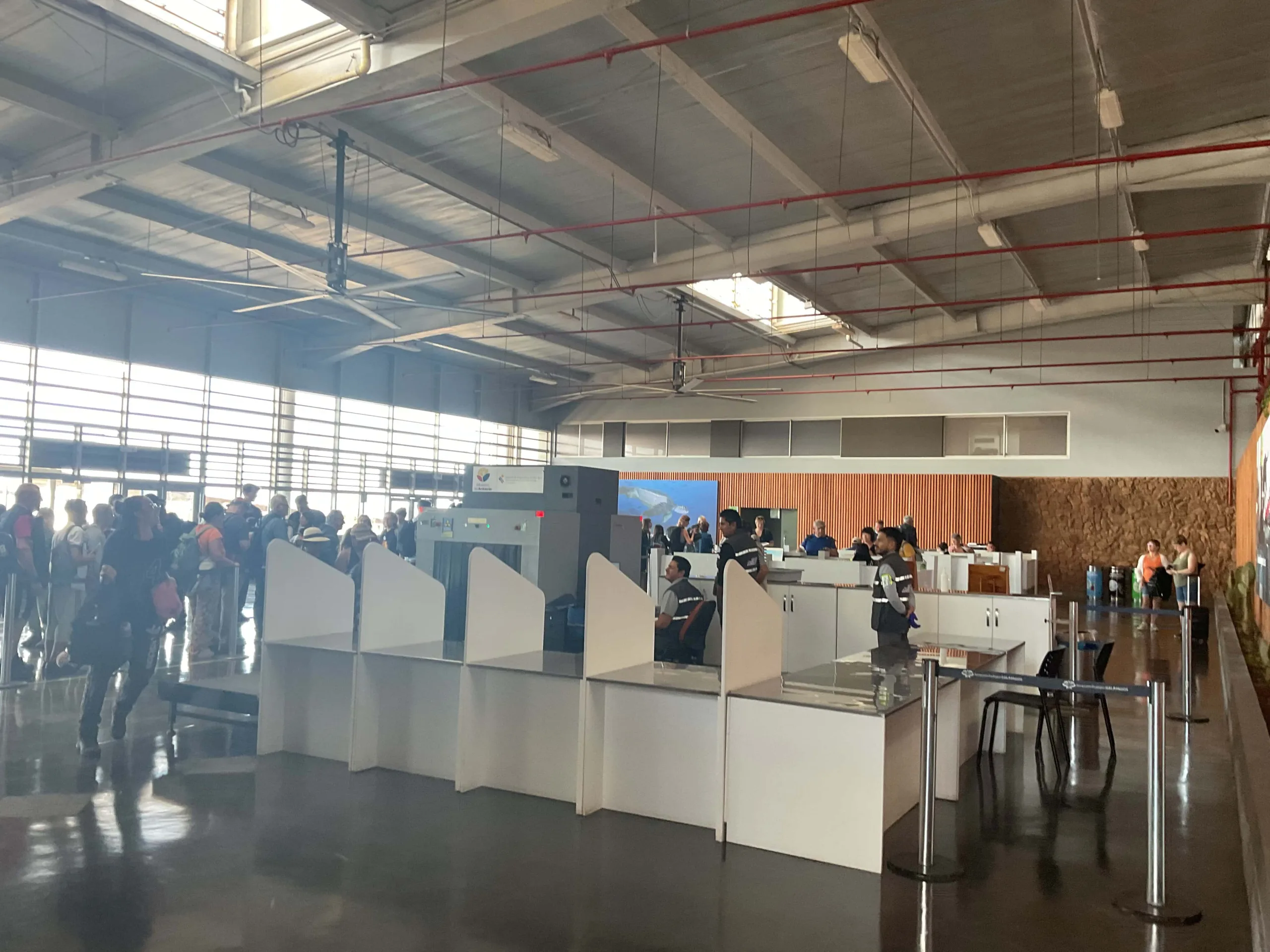 Tourists lining up in airport booths to pay the Galapagos entry fee in the Baltra Airport