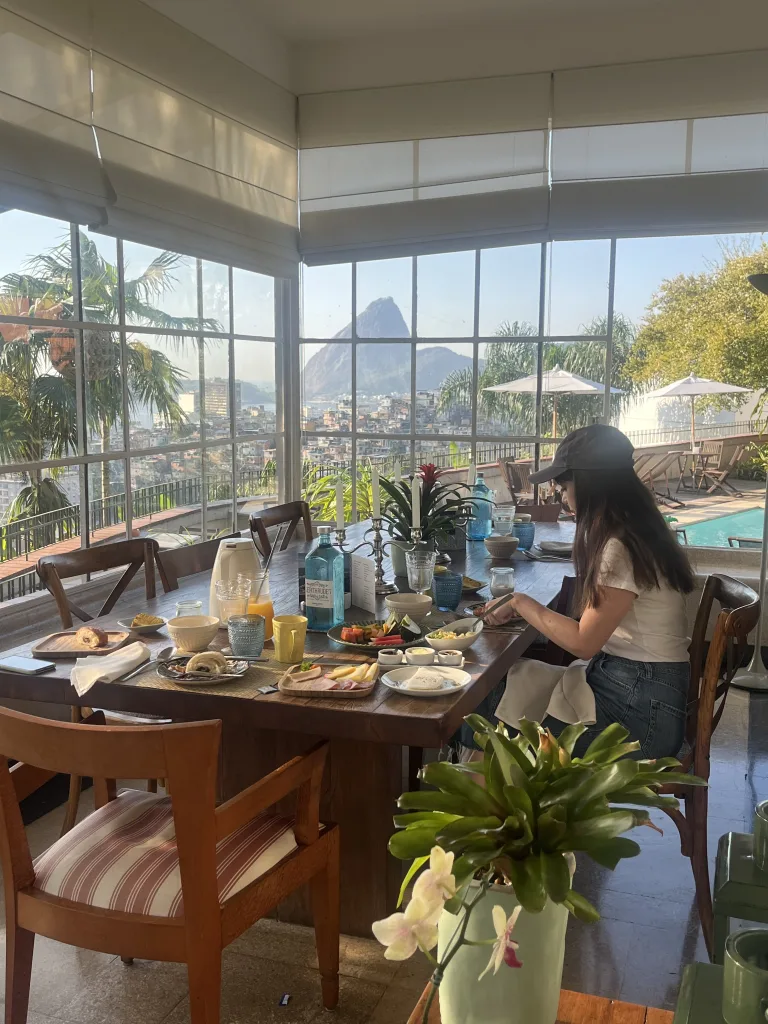Girl having breakfast at Gerthrudes in Rio. The breakfast room has glass walls that face the city and mount landscape of rio on a clear day.