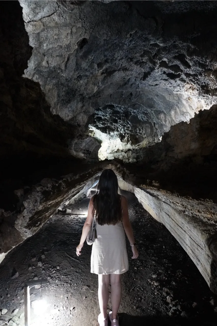 Girl walking inside a lava tunnel during the Highlands Tour in Santa Cruz