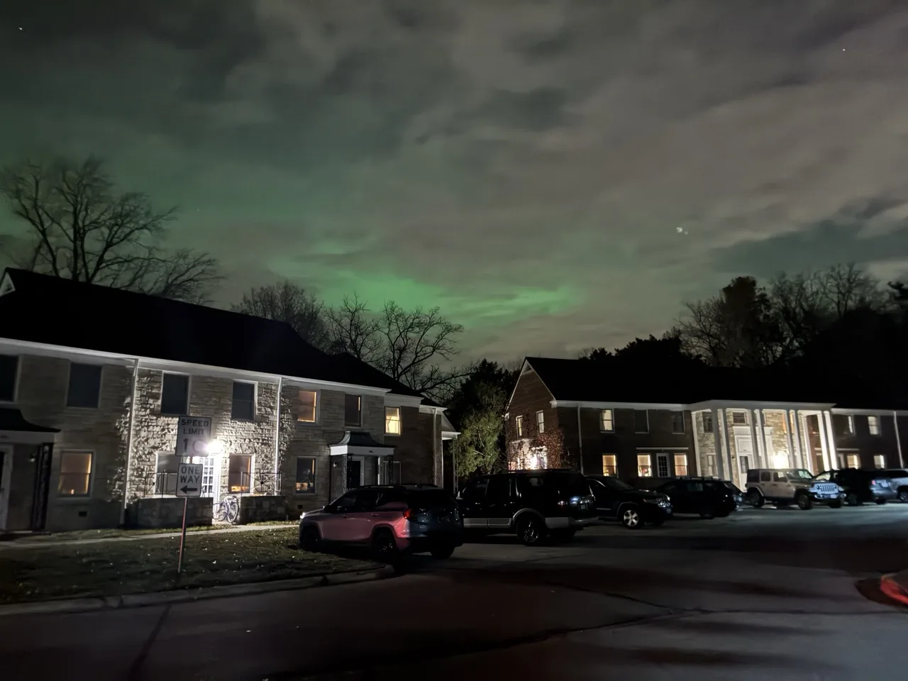Green tinted northwen lights shining behind clouds in a residential area of Madison, Wisconsin