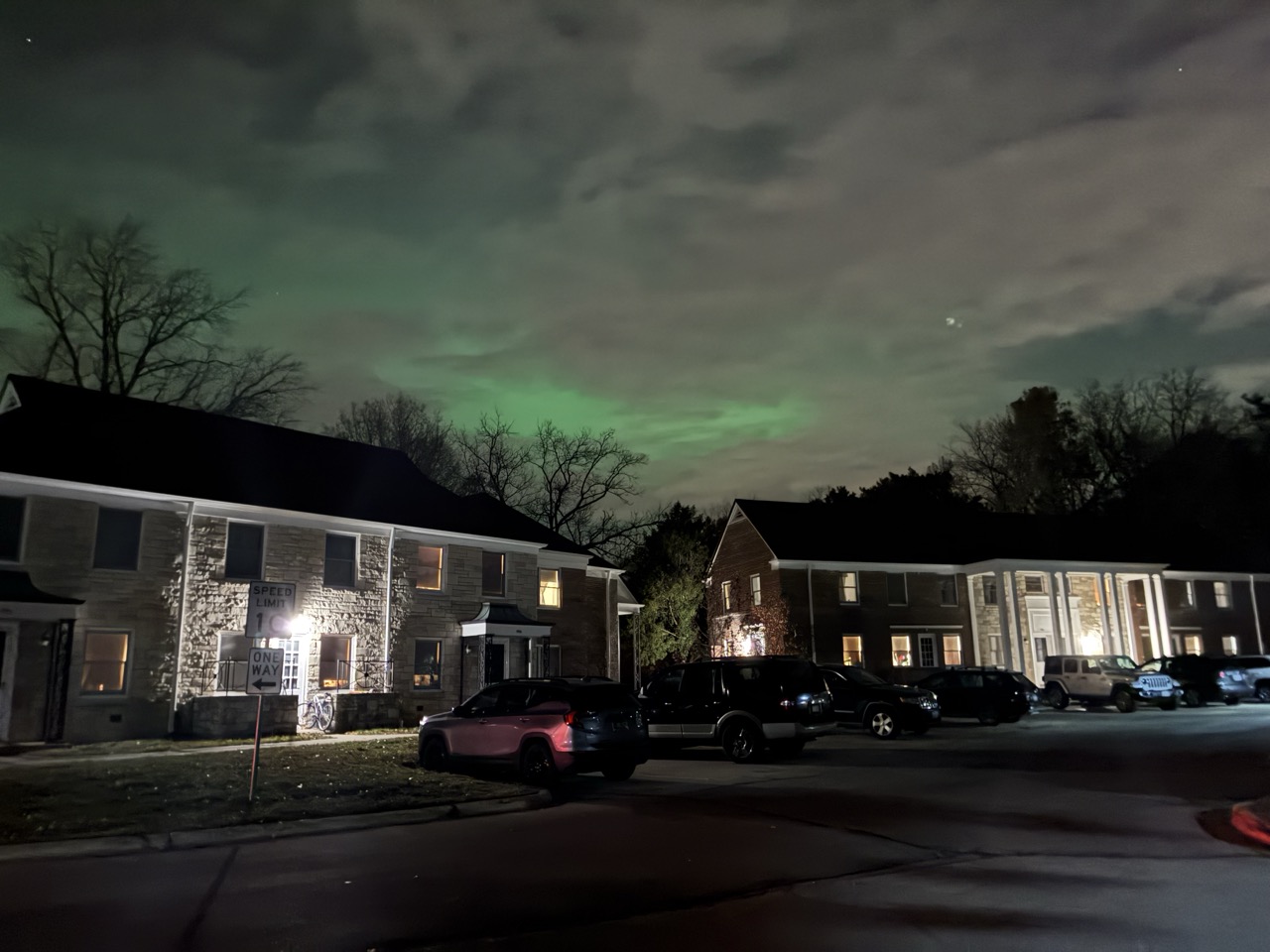 Green tinted northwen lights shining behind clouds in a residential area of Madison, Wisconsin