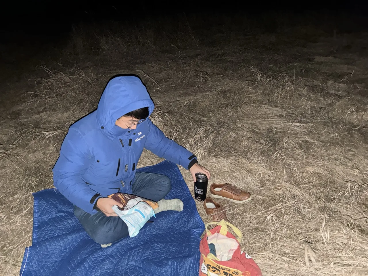 Man sitting and picnicking in the cold to watch the northern lights.